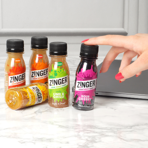 Hand grabbing Sour Cherry Zinger shot with a laptop in the background