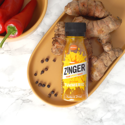 Organic Turmeric Zinger shot on a plate with ingredients